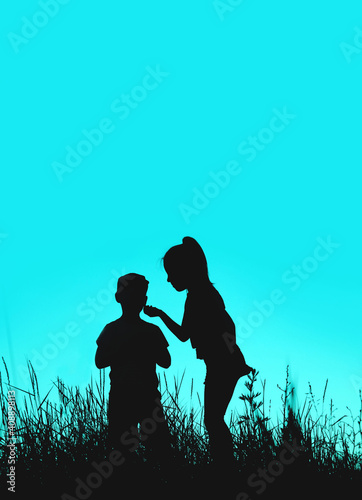 Blurry image of black silhouettes of brother and sister playing outdoors. People, family concept.