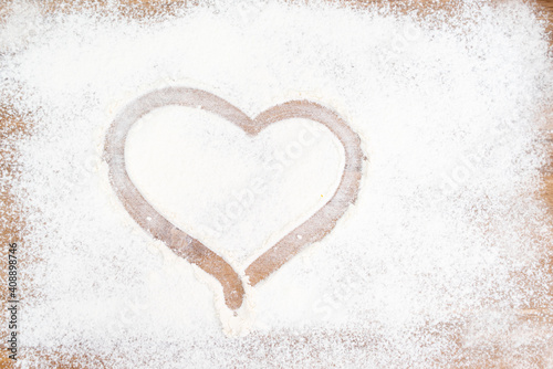 Drawn heart on a table strewn with flour. Drawing on flour