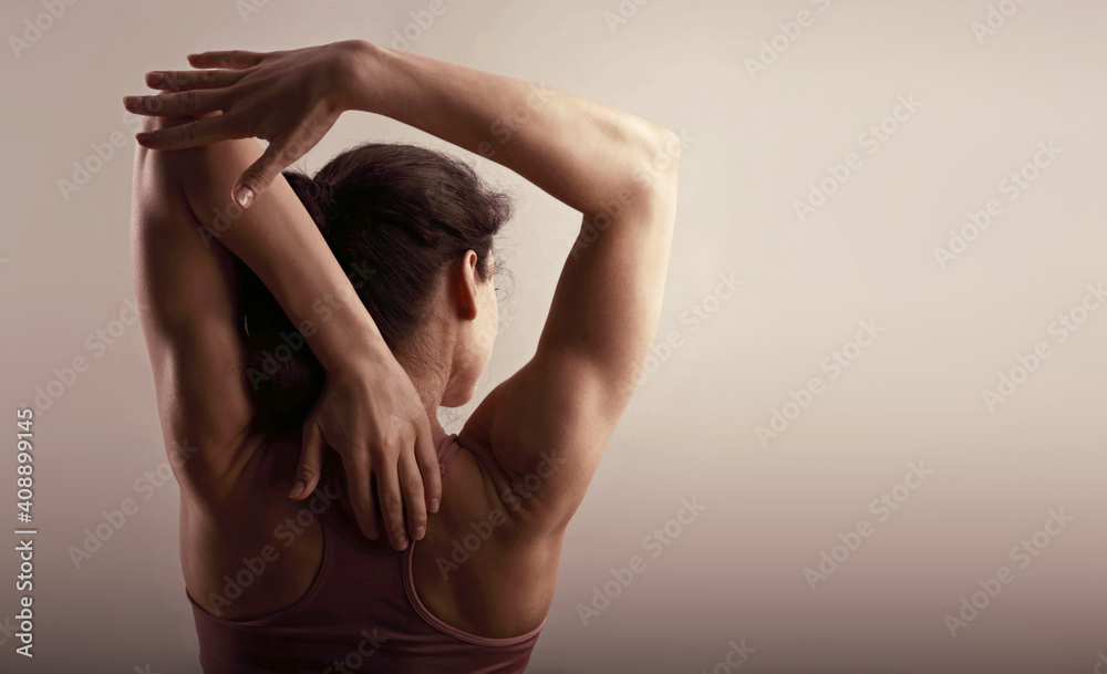 Sporty healthy body woman with strong shoulders and arms posing in sport top on grey background with empty copy space. Closeup portrait. The concept of healthy lifestyle and food.