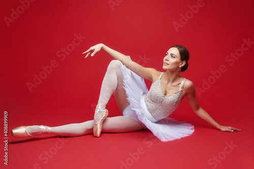 attractive ballerina poses in the studio on a red background