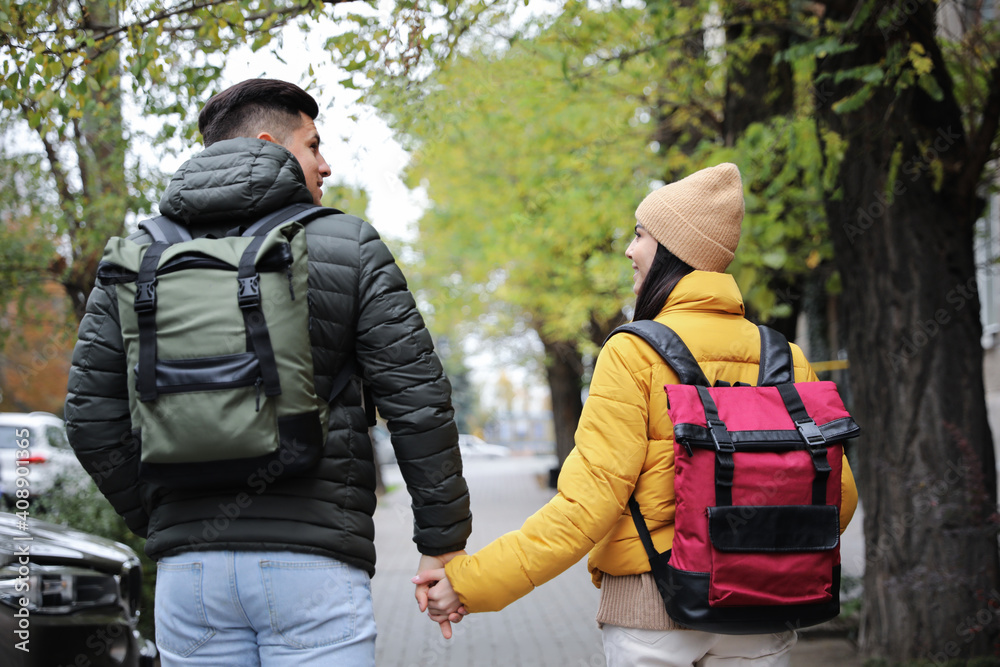 Couple with travel backpacks on city street, back view. Urban trip Couple with travel backpacks on city street, back view. Urban trip