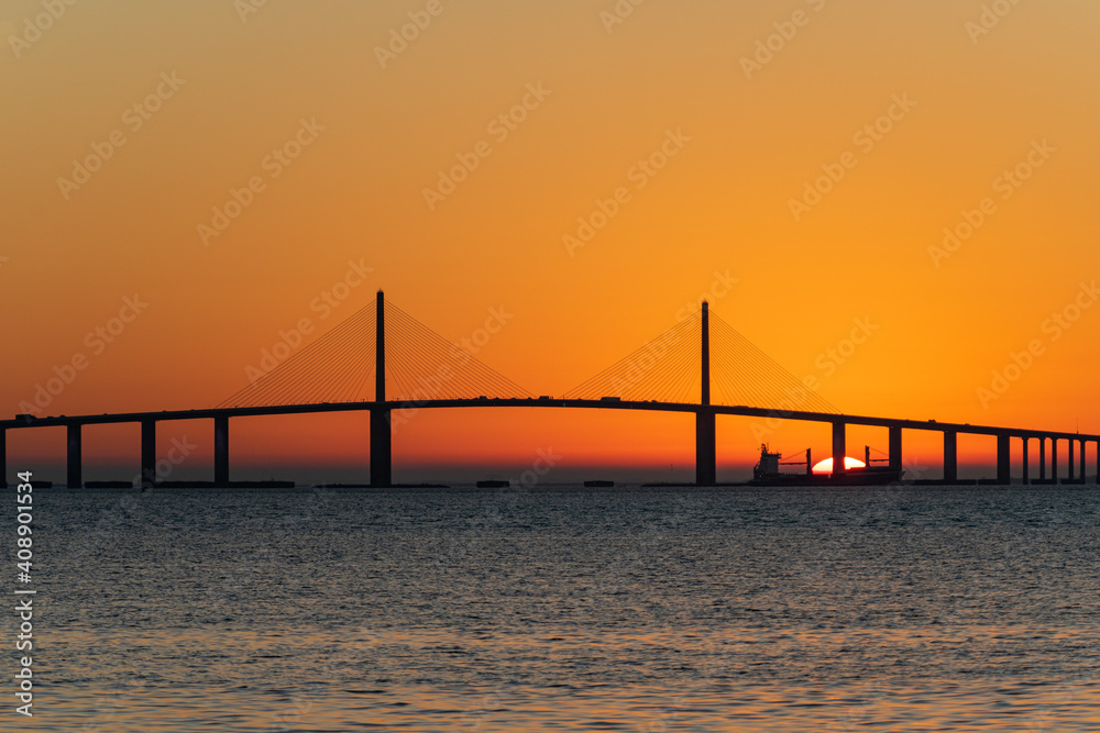 Sunrise behind freighter while sailing past bridge