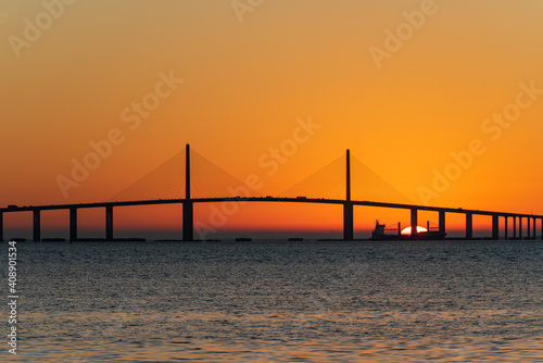 Sunrise behind freighter while sailing past bridge