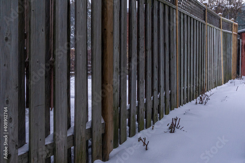Accumulation of snow along a wooden fence separating two backyards