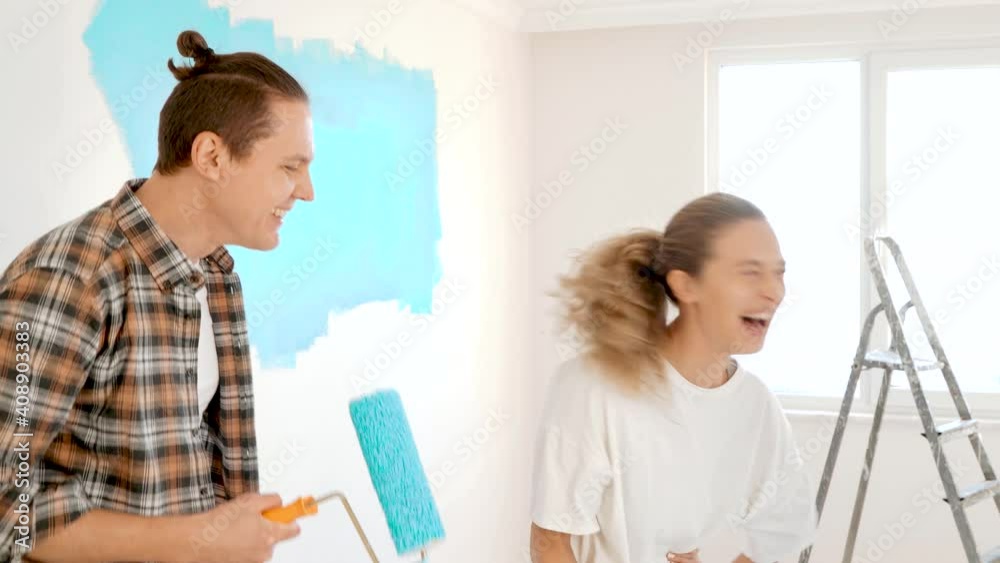Couple doing renovating at home and singing on paint roller. Renovation in cozy apartment flat, repair and makeover Couple doing renovating at home and singing on paint roller. Renovation in cozy apartment flat, repair and makeover