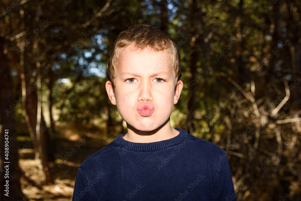 Young boy in a dark forest putting up duck faces to spoil a preadolescent photo Young boy in a dark forest putting up duck faces to spoil a preadolescent photo
