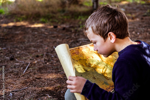 Foto A clever boy searches an ancient map for something buried in a forest