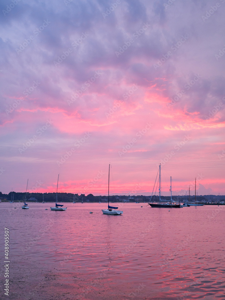 Stonington harbor pink sunset, purple clouds and sailboats. Stonington is the only coastal Connecticut harbor on the Atlantic Ocean.