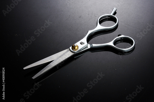 Metallic barber scissors on top of dark background.