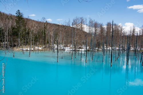 雪が残る春の青い池と冠雪の十勝岳 美瑛町 