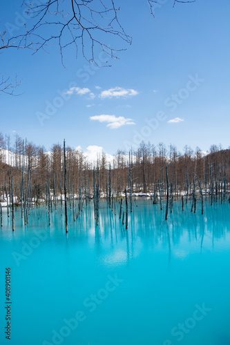 雪が残る春の青い池と冠雪の十勝岳 美瑛町