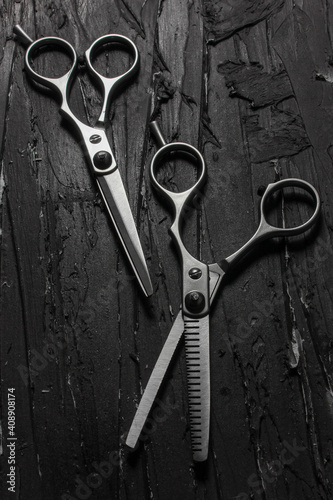 Metallic barber scissors on top of dark background.