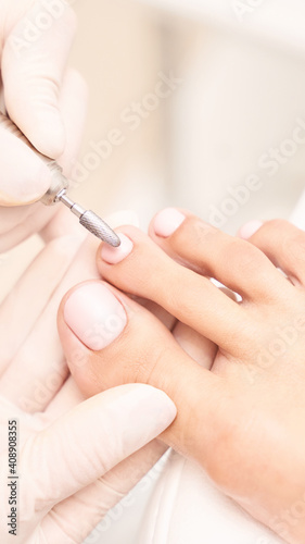 Beautiful salon procedure with pink pedicure on towel background. For decoration design. Healthcare. Woman body care. Spa treatment. White background. Nail machine polish. Medical