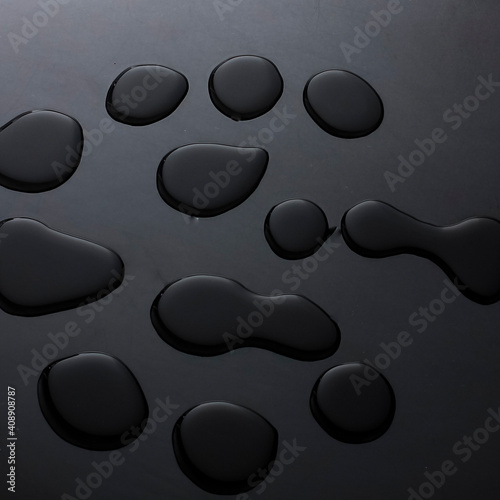 Abstract background of water droplets on black reflective table.