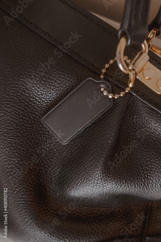 Black tag on genuine pebble leather bag with gold furnitureBlack tag on genuine pebble leather bag with gold furniture. Fashion brand name mock up, closeup, top view, copy space for text