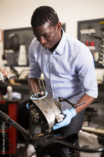 Portrait of afro american man master who is repairing motobike. High quality photo