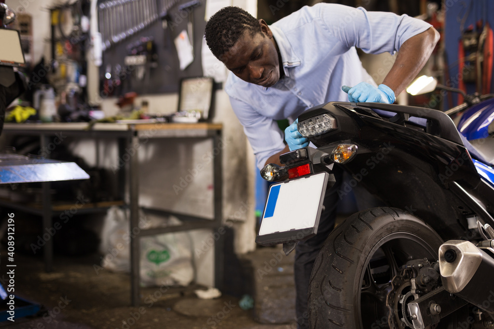 Afro american expert inspects the wheel of a motorcycle. High quality photo