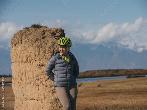 The woman travel on mixed terrain cycle touring with bikepacking. The traveler journey with bicycle bags. Sport bikepacking, bike, sportswear in green black colors. Mountain snow capped, stone arch. photo