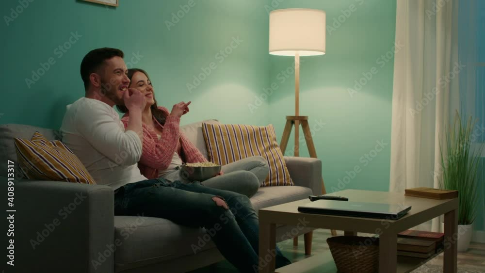 Happy woman and man have fun at home, eating popcorn and watching movie, spending weekend evening together, prefer to stay home, Slow motion. Happy woman and man have fun at home, eating popcorn and watching movie, spending weekend evening together, prefer to stay home, Slow motion.