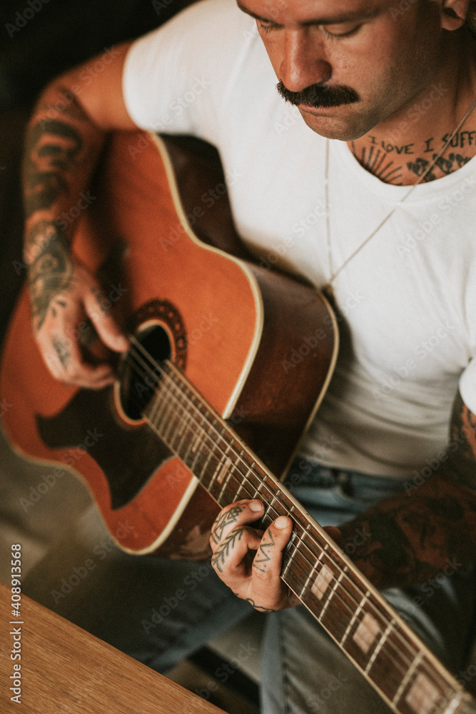 Obraz premium Tattooed singer songwriter playing an acoustic guitar