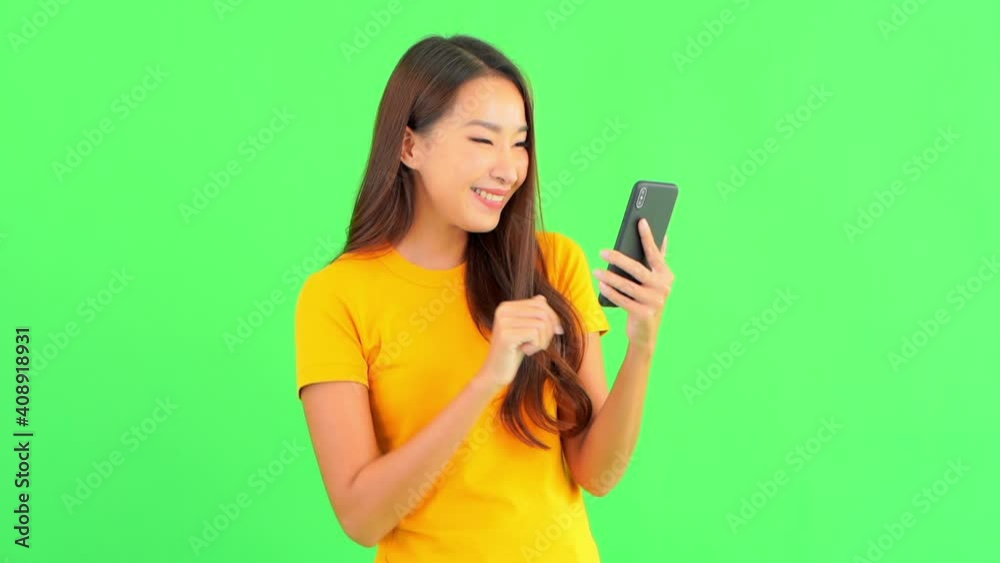 Young brunette woman using her mobile phone isolated on a green screen then surprised checking something and starts to celebrate as if she won a lottery. Young brunette woman using her mobile phone isolated on a green screen then surprised checking something and starts to celebrate as if she won a lottery.