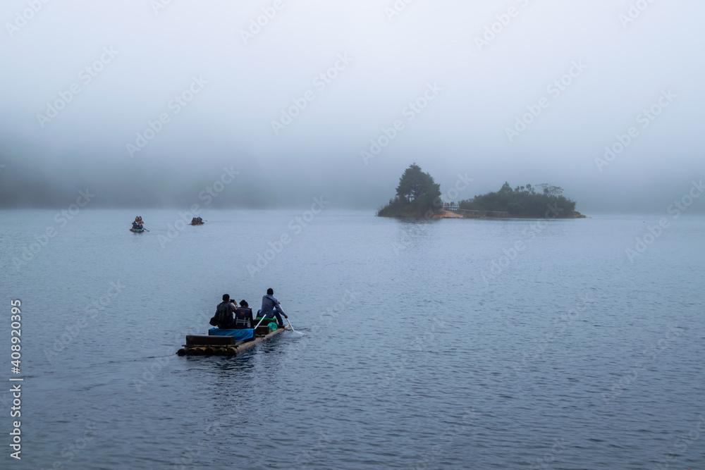 People on a wooden raft, on a foggy lake. Lagunas de Montebello, Chiapas, Mexico.