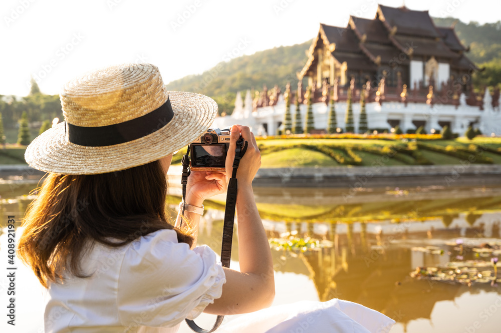 Rear view of tourist woman shooting beautiful view of Ho Kham Royal Pavilion an iconic symbol of Royal Park Rajapruek in Chiang Mai province of Thailand. 
