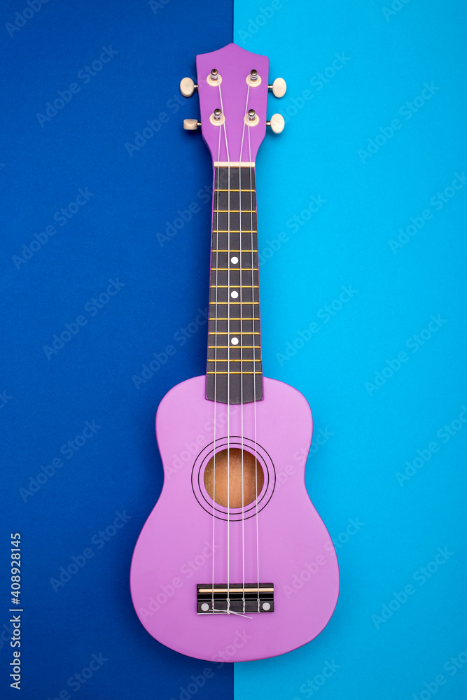 Obraz premium Four string ukulele guitar on blue background