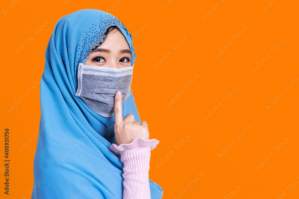 Asian muslim woman in medical mask to protect Coronavirus COVID-19 pandemic disease and say Shhhhh to keep warning quiet. Asian muslim woman in medical mask to protect Coronavirus COVID-19 pandemic disease and say Shhhhh to keep warning quiet.