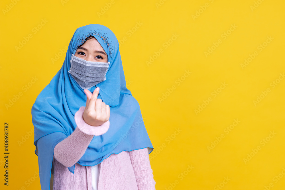 Asian muslim woman in medical mask to protect Coronavirus COVID-19 pandemic disease and showing lovely mini heart sign by her right hand.