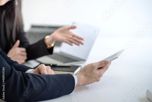 Businessman and businesswoman using touchpad and notebook in office meeting.