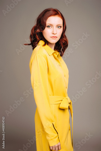 Young ginger woman in yellow shirt dress. Female bright look, lemon casual style. Fashion portrait on neutral studio background. photo