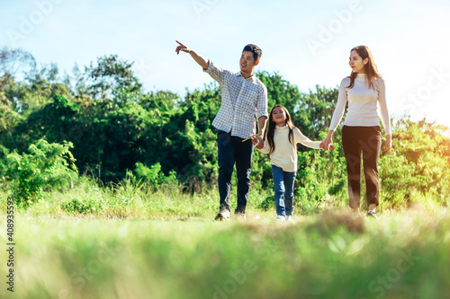 Girl with mother and father holding hands on the nature. Child with parents outdoors