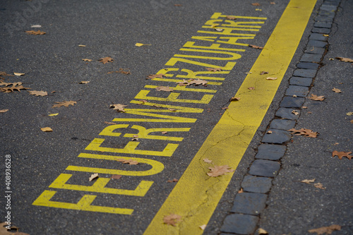 Yellow line on asphalt with text fire lane (german Feuerwehrzufaht).