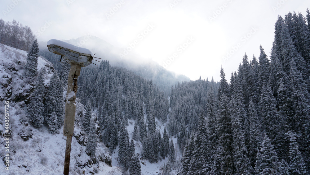 An old abandoned gazebo with views of the snowy mountains and forest. Clouds float beautifully, fir trees are covered with snow. High white hills. The stone pillars of the building are destroyed. An old abandoned gazebo with views of the snowy mountains and forest. Clouds float beautifully, fir trees are covered with snow. High white hills. The stone pillars of the building are destroyed.