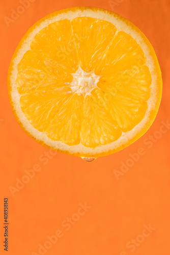 Slice of fresh orange on orange background. Copy space, macro, vertical orientation