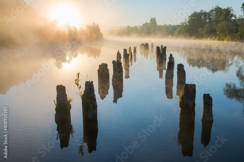 Misty morning on the river. Calm water and the remains of an old pier