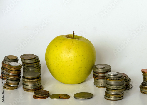 different shapes, countries and old metal coin values, beautiful green apple in the center, money storage and savings concept