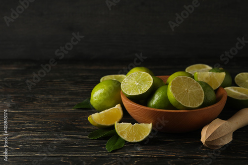 Bowl with ripe lime on wooden background, space for text