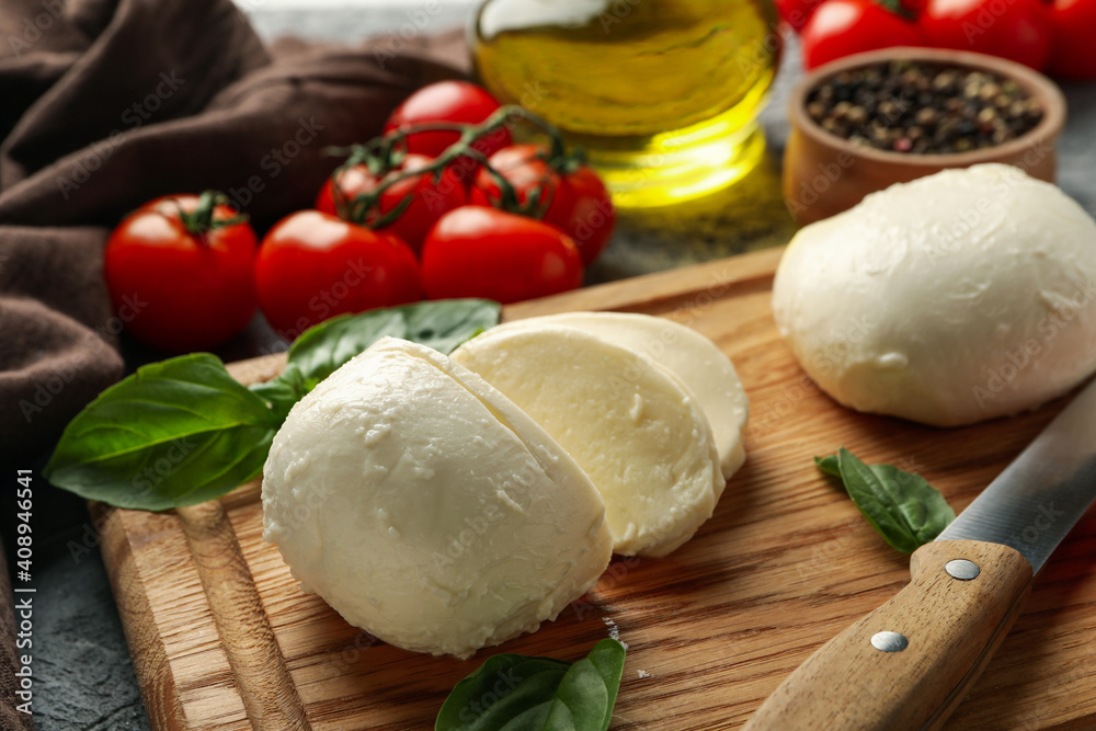 Concept of tasty eating with mozzarella on board on gray table, close up Concept of tasty eating with mozzarella on board on gray table, close up