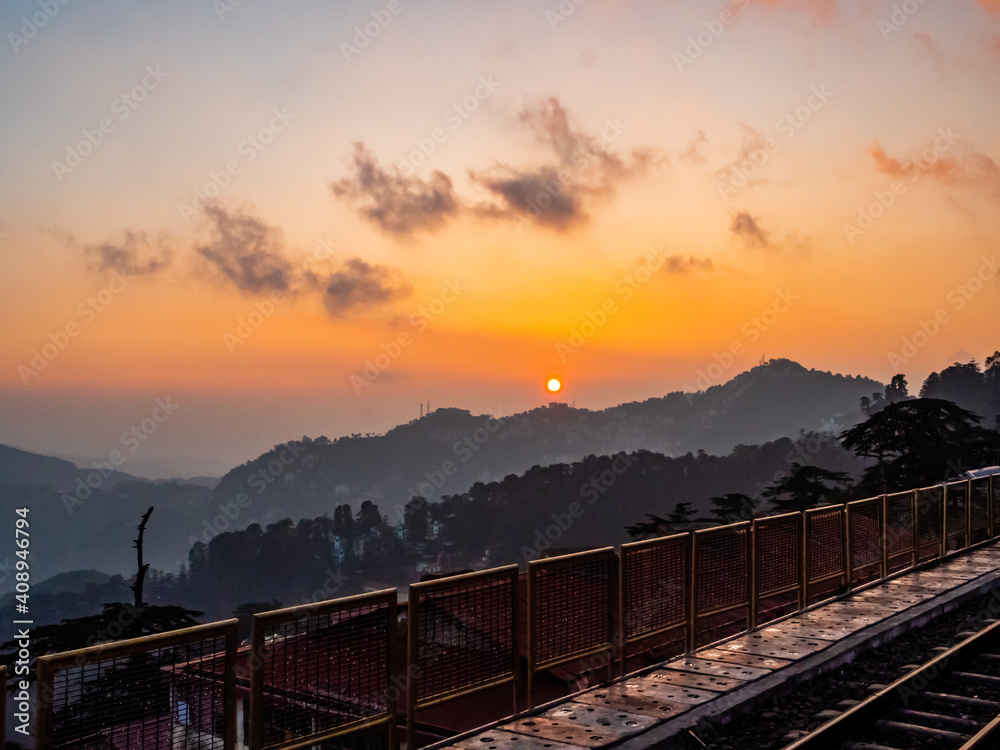 beautiful sunset behind mountains and railway track in the foreground