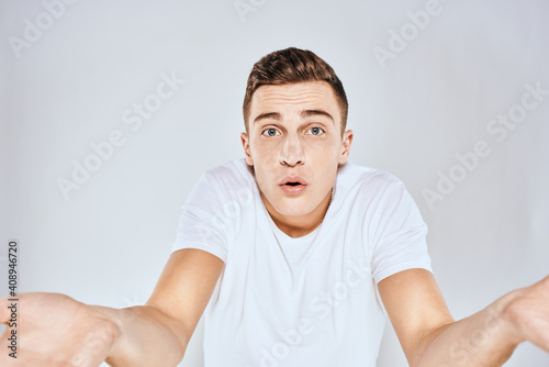 Nice man in a white t-shirt gestures with his hands emotions surprise studio