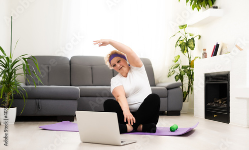 Domestic Training. Active Senior Woman Making Exersise In Front Of Laptop At Home, Free Space photo