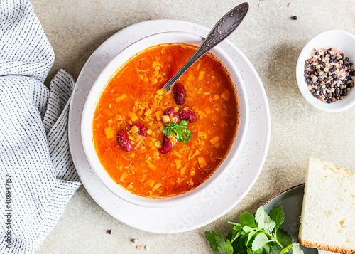 Homemade thick lentil and red bean soup with vegetables garnish with herbs. Fit and healthy, vegetarian and vegan meal. Top view.