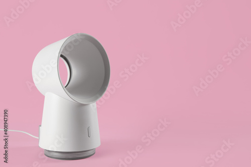 Modern electric fan on pink background. Space for text photo