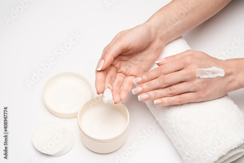 Closeup of beautiful female hand applying hand cream over grey backgroud