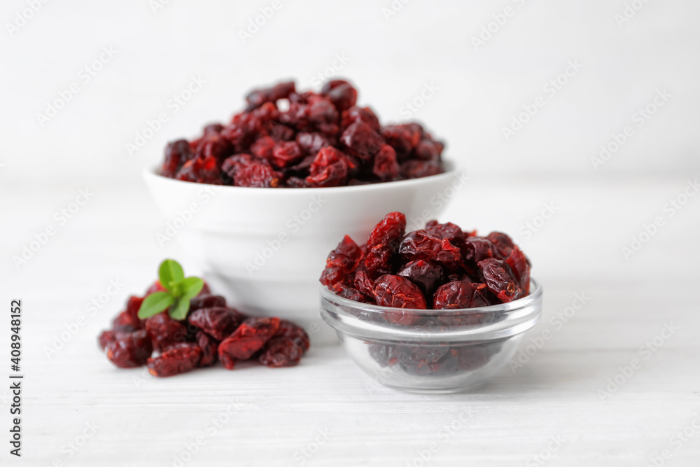 Tasty dried cranberries in bowls on white table Tasty dried cranberries in bowls on white table