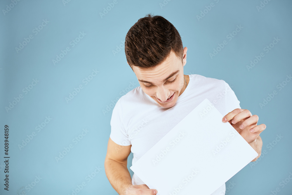 man holding a sheet of paper in his hands white t-shirt cropped view blue background man holding a sheet of paper in his hands white t-shirt cropped view blue background
