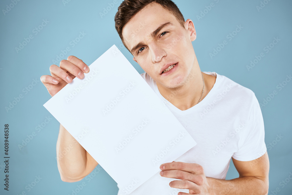a man in a white t-shirt holds a sheet of paper copy space a man in a white t-shirt holds a sheet of paper copy space