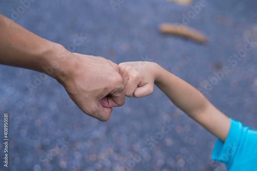 Little child and father bumping fists, man and child giving knuckle bump. © Nutt